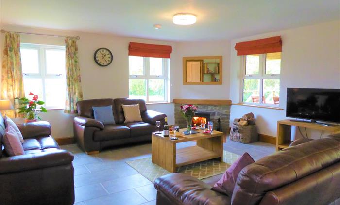 The spacious lounge has 3 comfy leather sofas, there is a log burning stove and a smart TV.  There are also books and games stored in the lounge for e